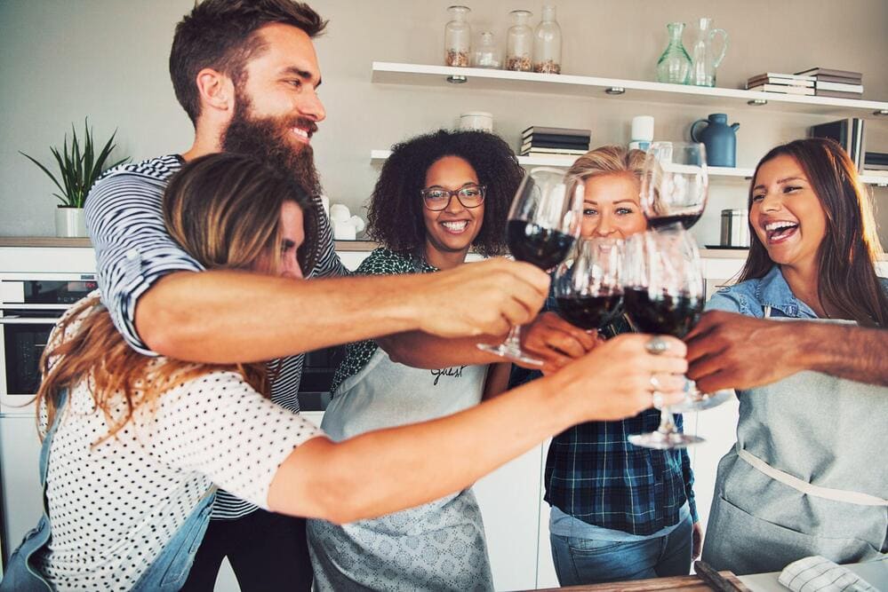 groupe de personnes qui passent du bon temps en trinquant avec un verre de vin rouge